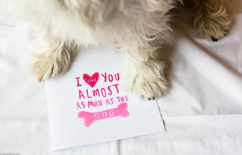 A valentine's card that says "I love you almost as much as the dog", and a dog in the background